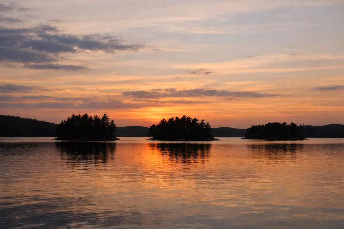 A calm lake with small wooded islands at sunset